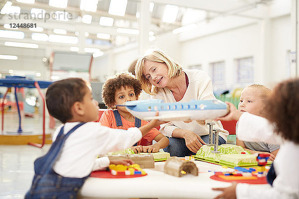 Teacher showing toy airplane to kids in science center