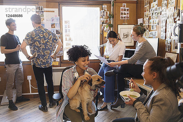 Creative business people with dog working and eating in office