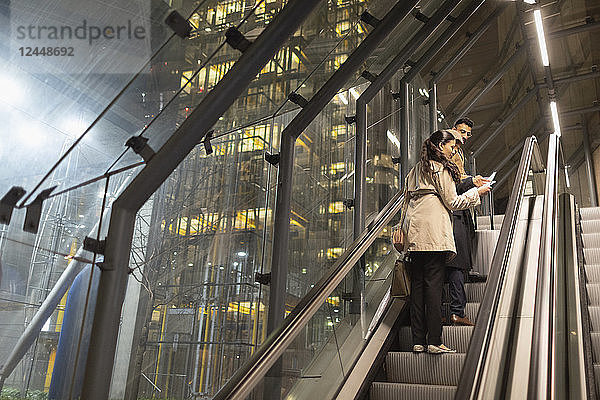 Business people with suitcase talking on urban escalator at night