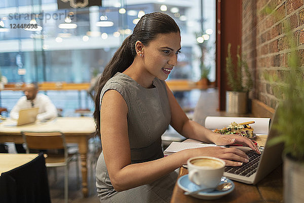 Businesswoman working at laptop in cafe