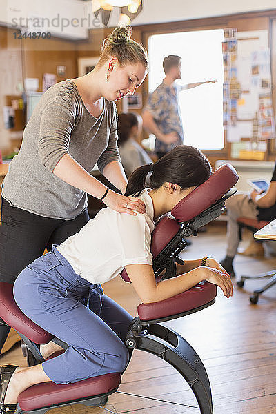 Creative businesswoman receiving massage from masseuse in office