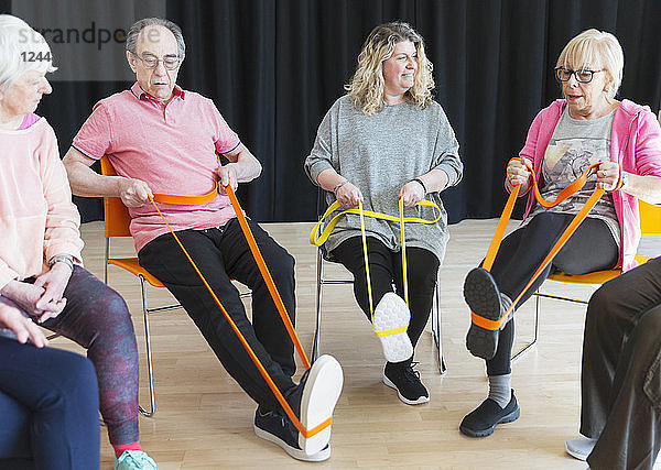 Active seniors exercising in circle  using straps to stretch legs