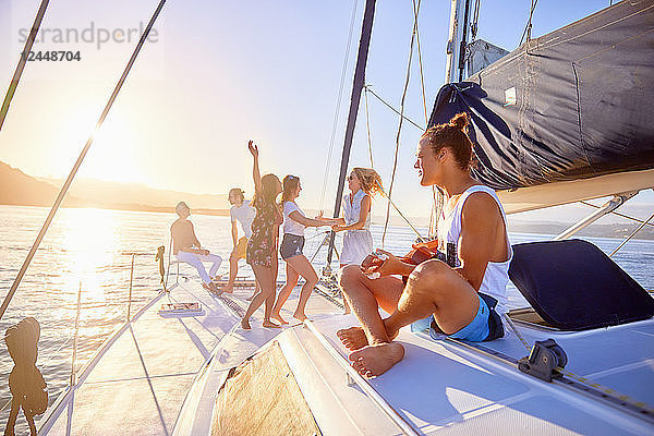 Playful friends dancing  playing guitar on sunny catamaran