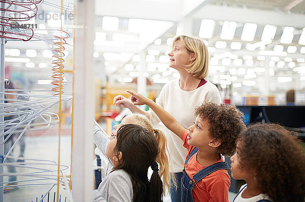 Teacher and curious students watching exhibit in science center