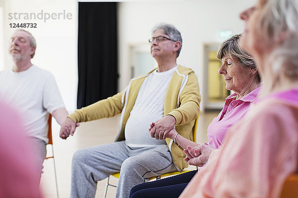 Serene active seniors holding hands  meditating