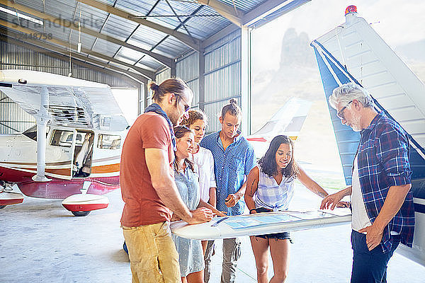 Friends planning trip at map in airplane hangar