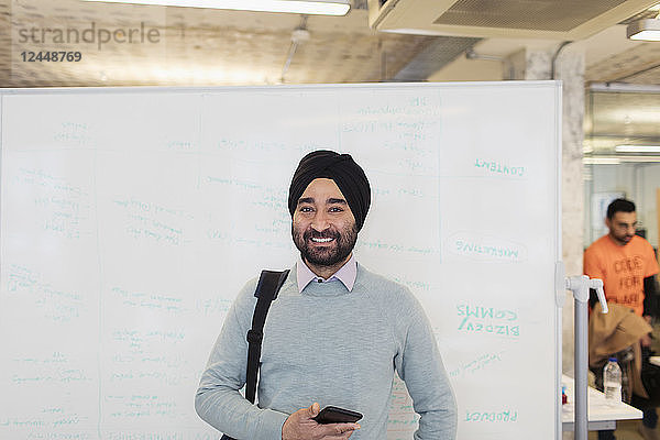 Portrait smiling  confident Indian businessman in turban standing at whiteboard in office