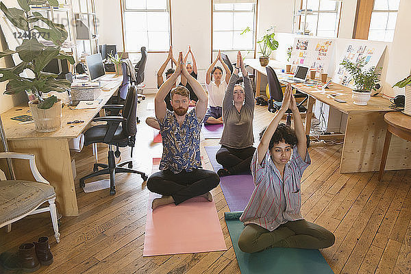 Creative business people practicing yoga in office