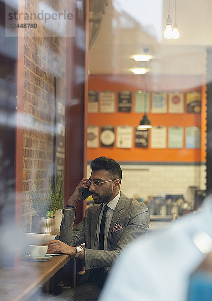Businessman talking on smart phone  working in cafe