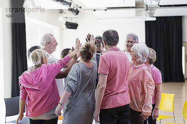 Active seniors high-fiving in circle huddle