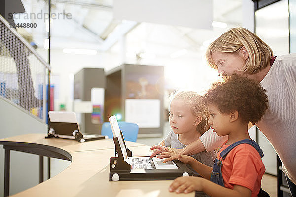 Teacher and schoolgirls using laptop in science center