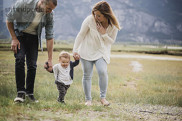 Parents walking with baby son in rural field