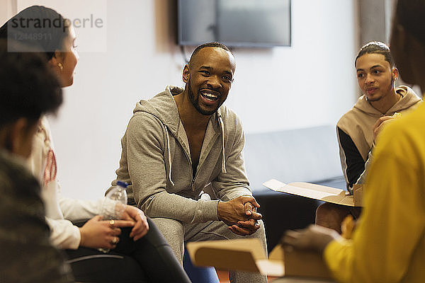 Smiling male mentor talking to teenagers in youth organization