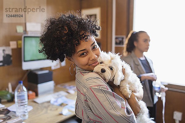 Portrait smiling creative businesswoman with cute dog in office