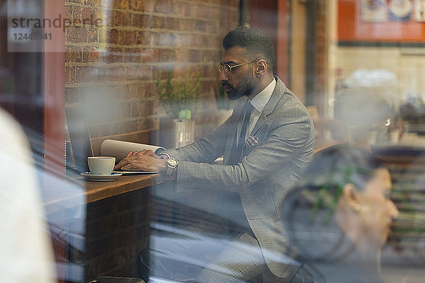 Businessman working at laptop in cafe