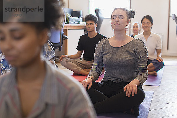 Serene creative businesswoman meditating in office