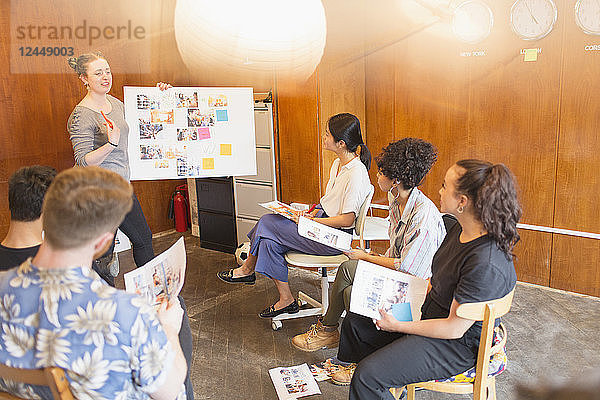 Creative designers brainstorming  reviewing photograph proofs in office meeting