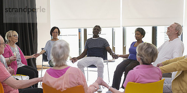 Serene active seniors holding hands  meditating in circle
