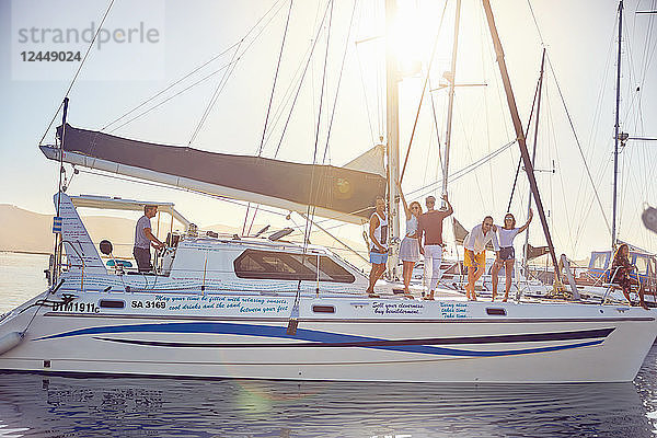 Portrait friends waving on catamaran in sunny harbor