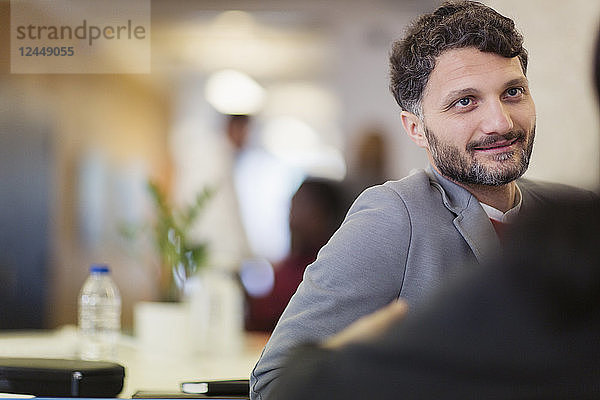 Smiling businessman listening to colleague in office