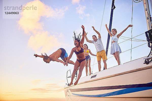 Playful friends jumping off boat