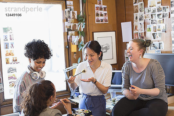 Creative female designers eating sushi in office