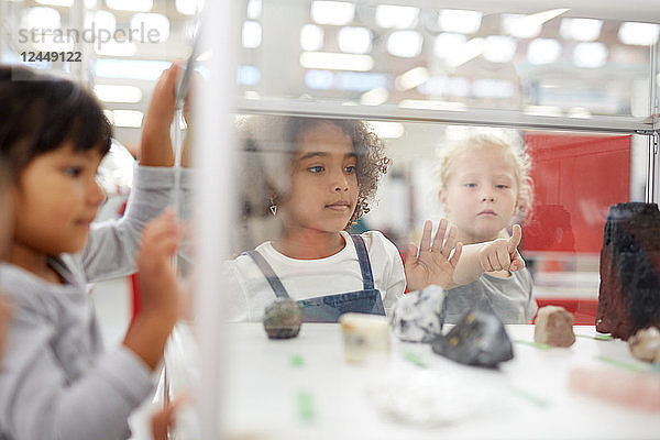 Curious kids looking at rocks in display case in science center