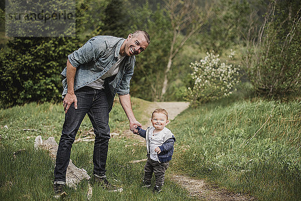 Portrait father and baby son walking on grassy path