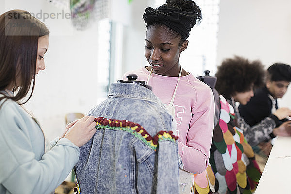 Teenage girls designing denim jacket in fashion design class