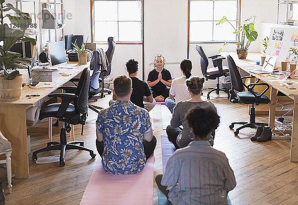 Creative business people meditating in office