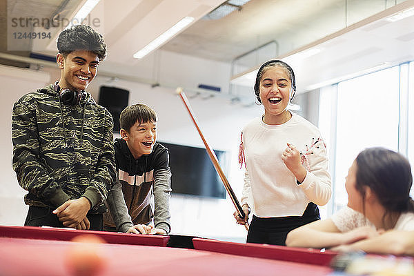 Happy teenagers playing pool in community center