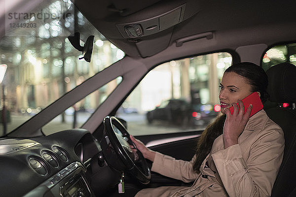 Businesswoman talking on smart phone in car at night