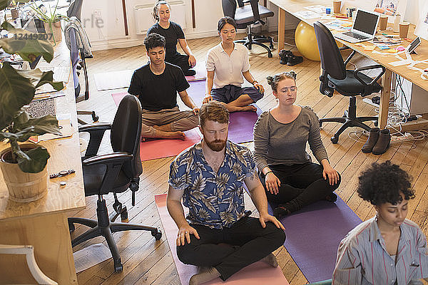 Serene creative business people meditating in office