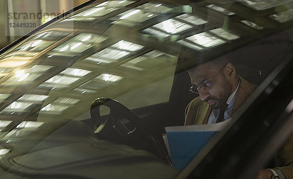 Businessman reviewing paperwork in car at night