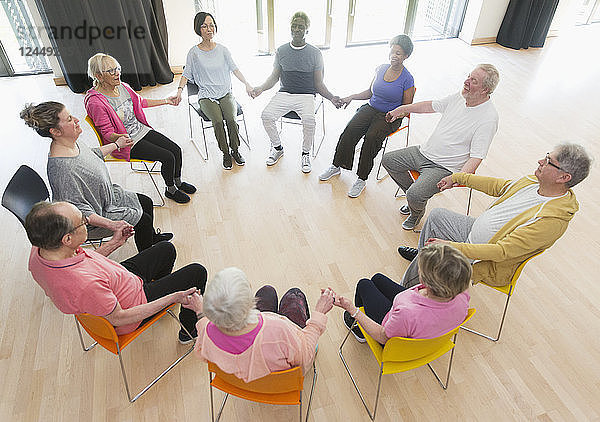 Active seniors holding hands in circle  meditating in community center