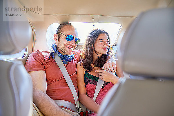 Affectionate couple riding in back seat of car