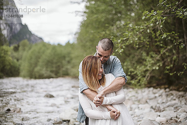 Affectionate couple hugging along stream