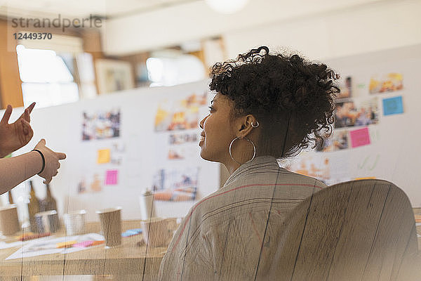 Creative female designer listening to colleague in office