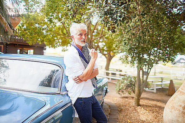 Portrait confident man biting tip of eyeglasses at car