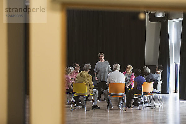 Woman leading seniors in group discussion in community center