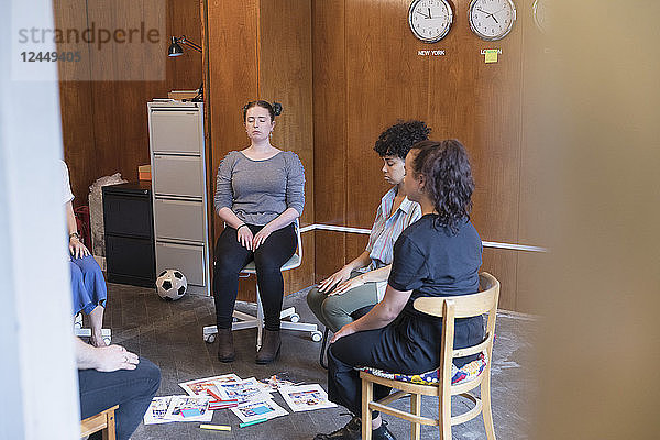 Serene  creative businesswomen meditating in circle  taking a break in meeting