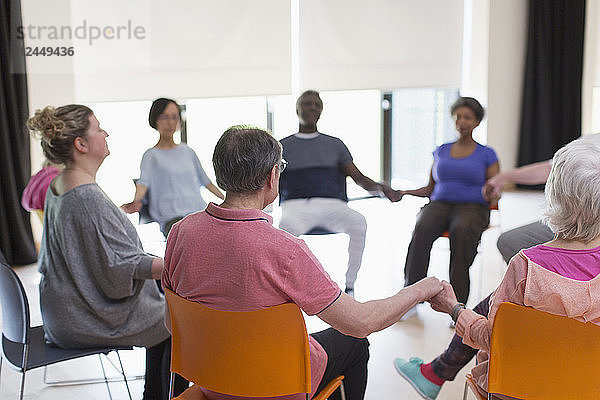 Serene active seniors holding hands  meditating in circle