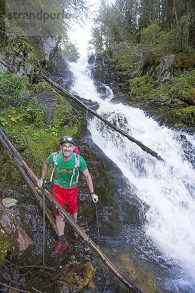 Ein männlicher Wanderer ist klatschnass  nachdem er einen Fluss mit Wasserfall im Val Danniviers überquert hat