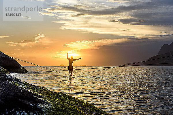 Slacklining am Strand von Arpoador während des dramatischen Sonnenuntergangs  Rio De Janeiro  Brasilien