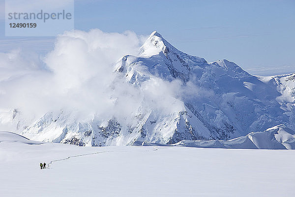 Zwei Bergsteiger überqueren einen Gletscher auf dem Mt. McKinley  Alaska. Im Hintergrund ist der Mount Hunter zu sehen. Der Mount McKinley (einheimischer Name Denali) ist der höchste Berg Nordamerikas mit einer Gipfelhöhe von 6.194 m über dem Meeresspiegel. Mit einer Höhe von rund 5.500 m (18.000 Fuß) ist der Anstieg von der Basis bis zum Gipfel der größte aller Berge  die sich vollständig über dem Meeresspiegel befinden. Gemessen an der topografischen Ausdehnung ist er nach dem Mount Everest und dem Aconcagua der drittgrößte Berg. Der McKinley befindet sich in der Alaska Range im Inneren des US-Bundesstaates Alaska und ist das Herzstück des Denali National Park and Preserve.