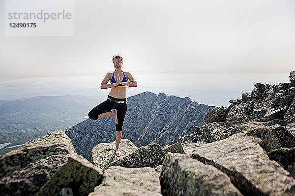 Eine junge Frau praktiziert Yoga auf dem Gipfel des Mount Katahdin  Maine.