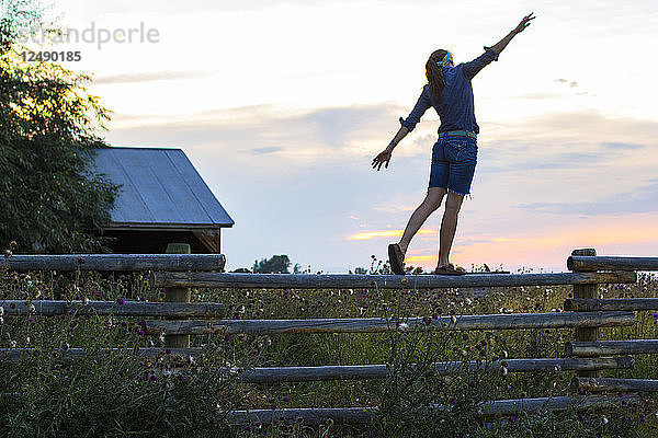 Eine Frau balanciert auf einem Spaltzaun auf einer Ranch in Bozeman  MT  im Sommer.