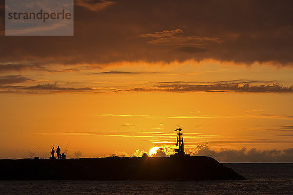 Silhouette eines Fischers  der den Sonnenuntergang an der Nordküste von Oahu  Hawaii  genießt