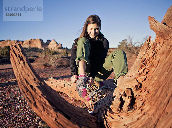 Eine junge Frau wechselt ihre Socken in der Wüste.