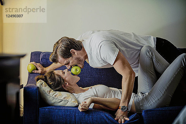 Ein süßes junges Paar isst Apfel auf einem Sofa in einem Hotelzimmer in Dallas